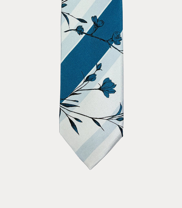 Cravatta Fabio Toma in seta avorio e celeste con fiori blu e fascia diagonale blu petrolio.