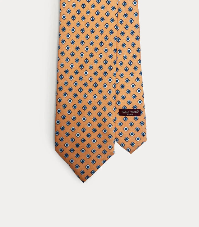 Cravatta Fabio Toma Roma in seta arancione con micro pattern geometrico blu e bianco, vista frontale.