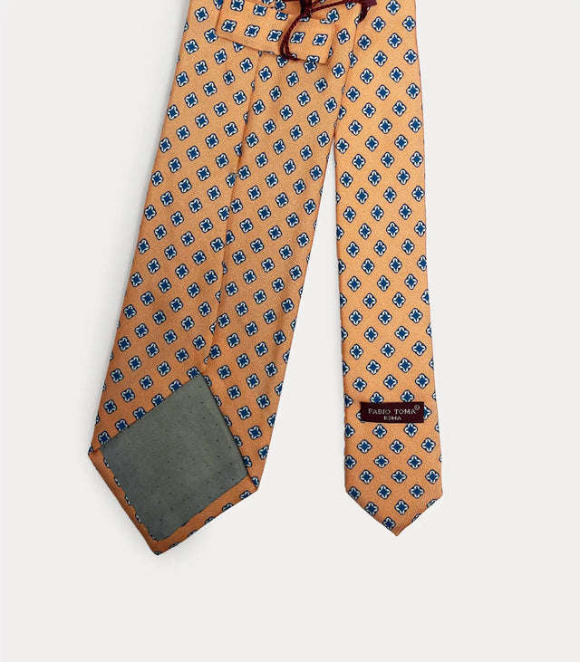 Primo piano del pattern geometrico su seta arancione e dettaglio dell'etichetta Fabio Toma Roma.