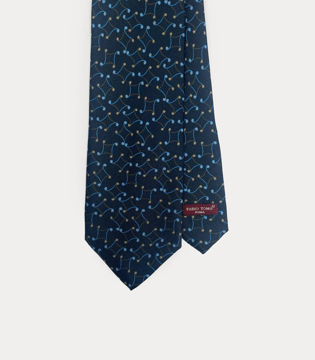 Dettaglio frontale della cravatta Fabio Toma Roma in seta blu navy con motivo a volute azzurre e beige, etichetta visibile.