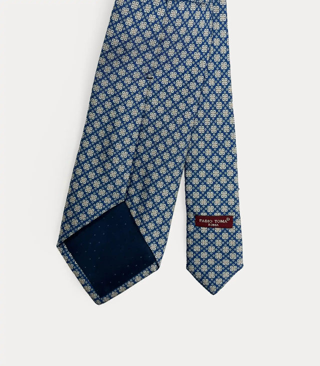 Vista posteriore della cravatta blu in seta che mostra il passante sartoriale, le finiture fatte a mano e l'etichetta del brand.