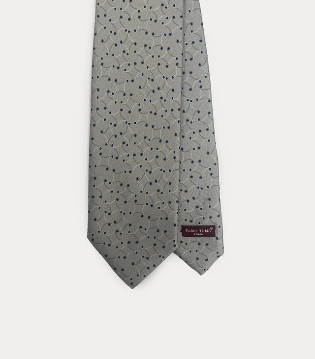 Dettaglio frontale della cravatta Fabio Toma Roma in seta grigia con pattern a pois blu e volute sottili, etichetta visibile.