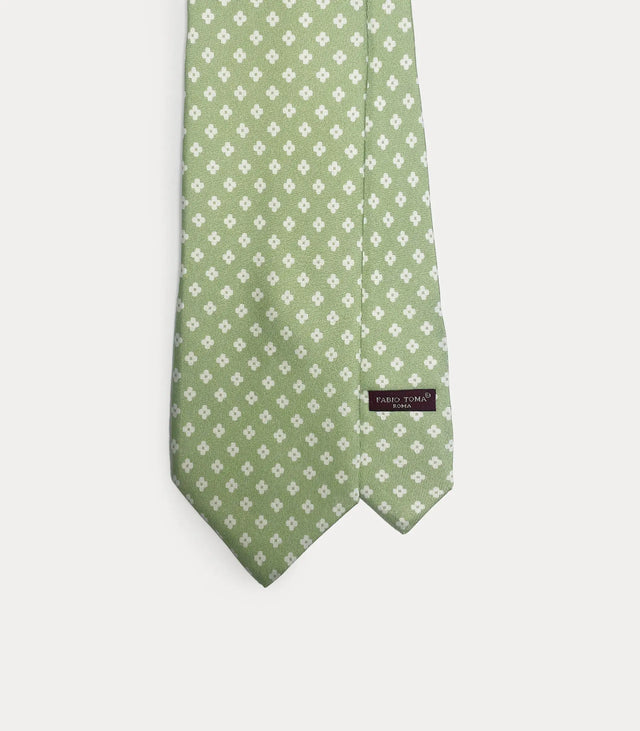 Cravatta Fabio Toma Roma in seta verde salvia con micro pattern di fiori bianchi, dettaglio del nodo e della trama.