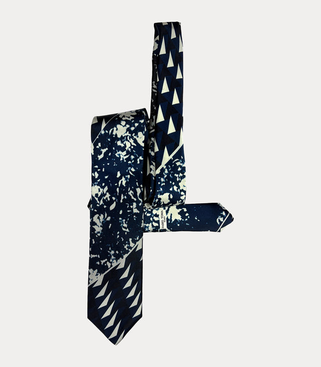 Cravatta blu navy e avorio con fantasia astratta e geometrica, ripiegata con logo Fabio Toma Roma visibile sul codino.