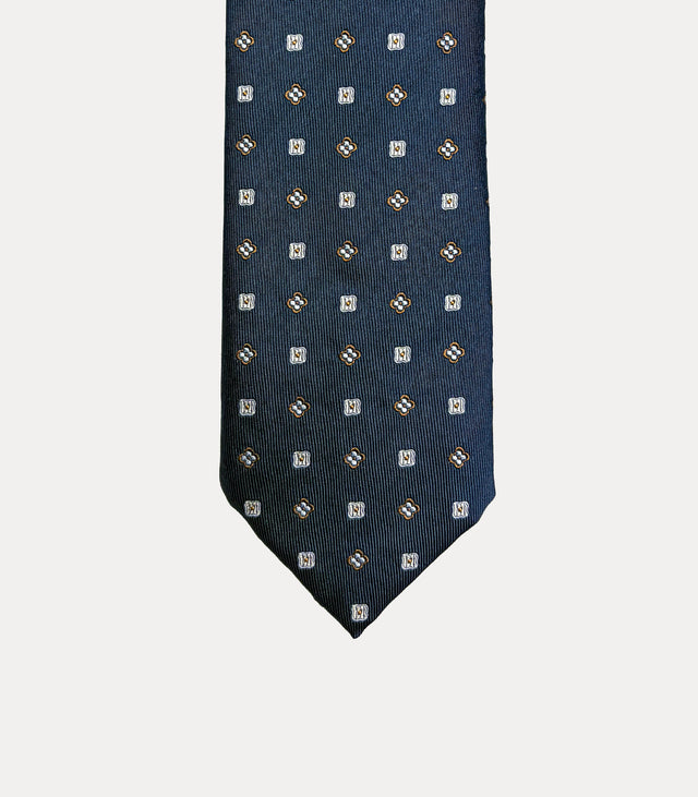 Cravatta Fabio Toma Q931 in seta blu navy con piccoli fiori stilizzati e quadrati avorio e ocra.