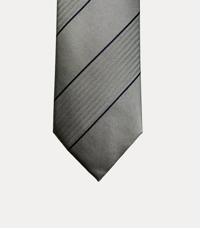 Cravatta Fabio Toma in seta grigio argento con righe diagonali blu scuro e bande a spina di pesce.