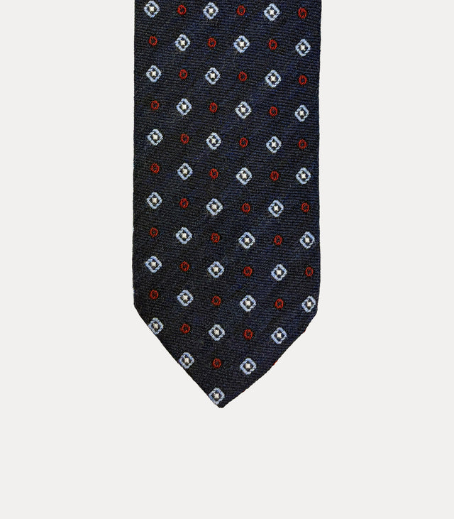 Cravatta Fabio Toma Q813 in pura lana blu navy con rombi celesti, centri avorio e piccoli cerchi rossi.