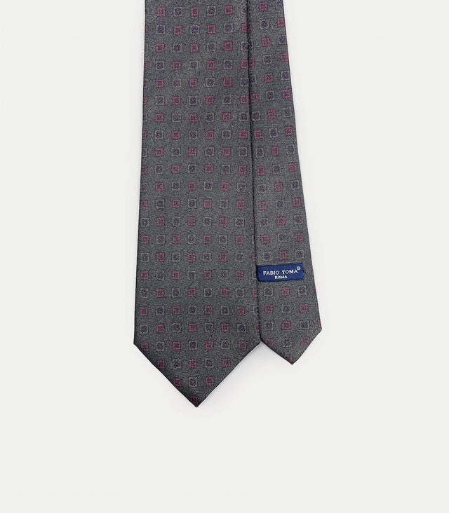 Cravatta grigio scuro in seta con motivo geometrico rosso e blu